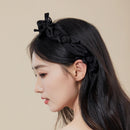 Close-up of handwoven bow detail and rose embroidery on black hairband