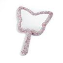 White teardrop-shaped crystal mirror displayed upright on marble surface