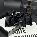 Side angle showing oversized shark-clip mechanism and velvet bow structure