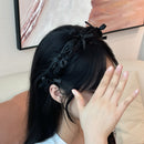 Side view of textured black headband showing sculpted crown lift and dimensional bow detail