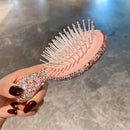 Close-up of flexible bristles and cushion base on pink-and-pink cushion hairbrush