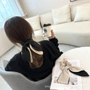 Side angle of beige bow hair tie highlighting dimension and drape