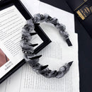Close-up of crystal accents and ruffled edge on black satin hair hoop