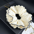 Close-up of hand-stitched camellia motif on white hair tie