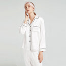 White silk pajama set with contrast piping shown on model wearing matching headband
