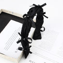 Black wide cream cake-inspired headband with ruffled bow on white background