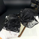 Close-up detail of satin bow and rose accents on black shark clip