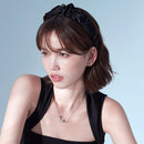 Black satin headband worn on model with low bun and natural lighting