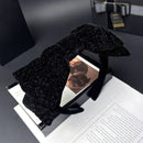 Close-up of black velvet bow headband showing textured fabric and silver-plated bow knot