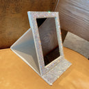 Minimalist flat lay with mirror, small succulent, and gold hair clips on marble surface