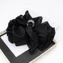 Lifestyle image of black bow clip securing a low half-up hairstyle on model