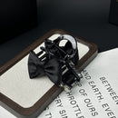 Flat lay of SUUMEE ribbon bow claw clip beside branded matte gift box and tissue paper