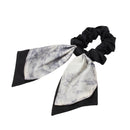 Three-color set of bow hair ties arranged on marble surface