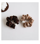 Overhead view of black pearl hair tie wrapped around wrist for scale