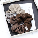 Close-up of ruched fabric folds and double-tone seam on coffee brown scrunchie