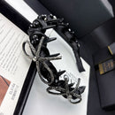 Side angle showing textured wave band and smooth satin finish of black headband