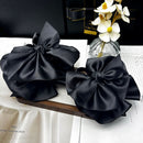 Side angle showing wide-toothed metal frame and layered satin bow detail