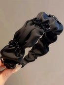 Black headband folded flat showing flexibility and smooth satin finish