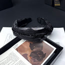 Flat lay of black rhinestone hair band on soft beige linen, top-down view