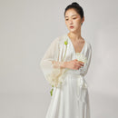 Model holding white poppy flower wearing silk loungewear robe