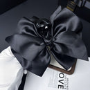 Close-up of satin texture and precise stitching on black bow hair clip