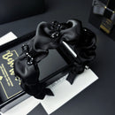 Front view of black crystal bow satin hair band on white background