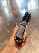 Lifestyle image: mirror comb resting on bathroom countertop with towel and perfume