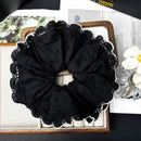 Black camellia ribbon hair tie laid flat on marble surface