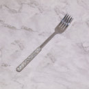 Silver flatware set placed beside ceramic dinner plate and wine glass — elegant table setting